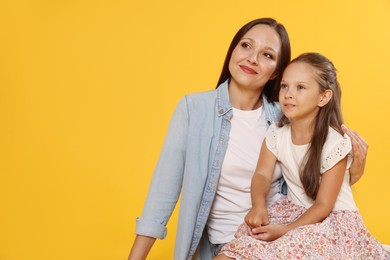 Photo of Lovely mother and daughter on yellow background. Space for text