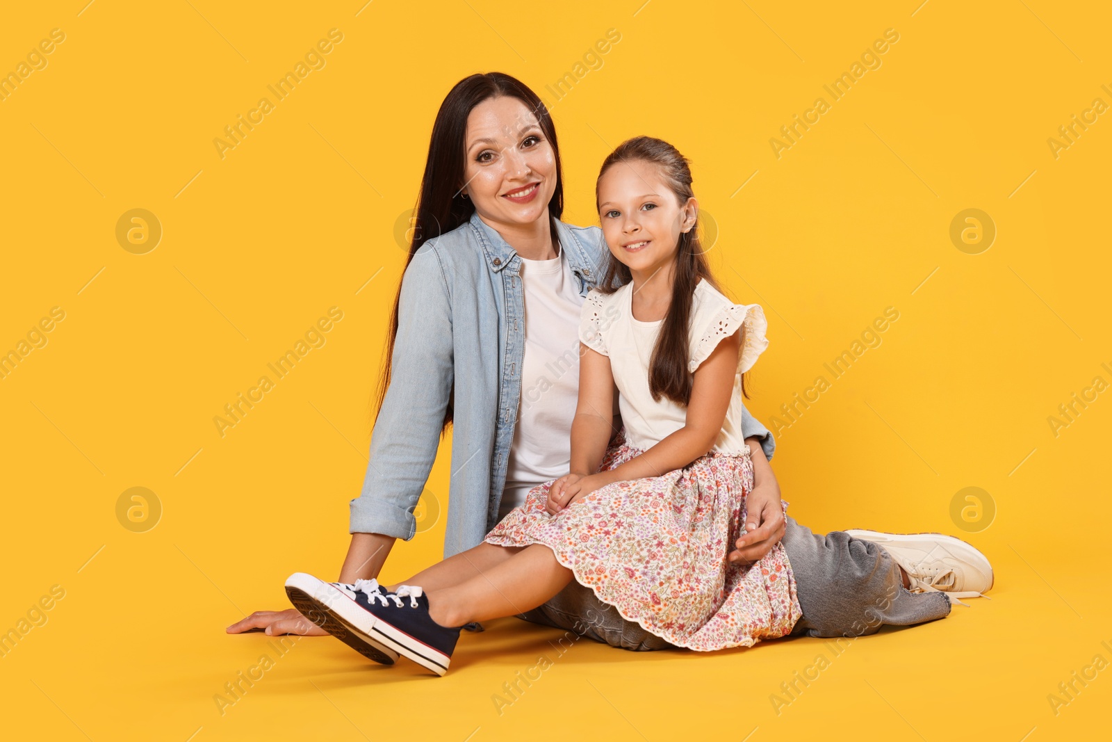 Lovely mother and daughter on yellow background Photo of Lovely mother and daughter on yellow background
