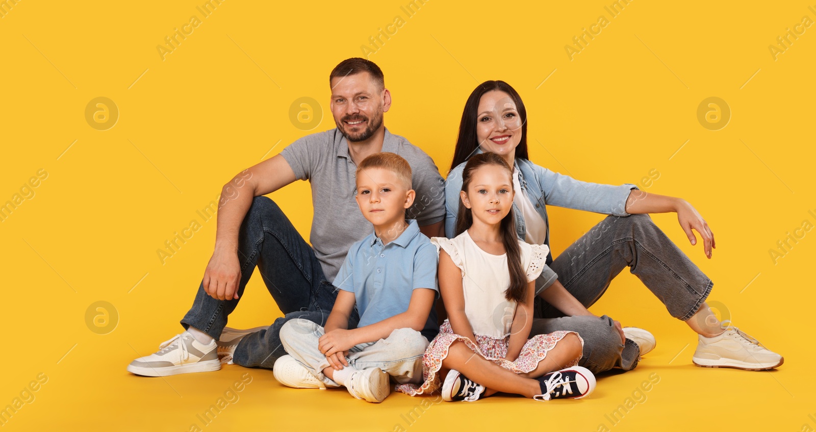 Lovely family posing together on yellow background Photo of Lovely family posing together on yellow background