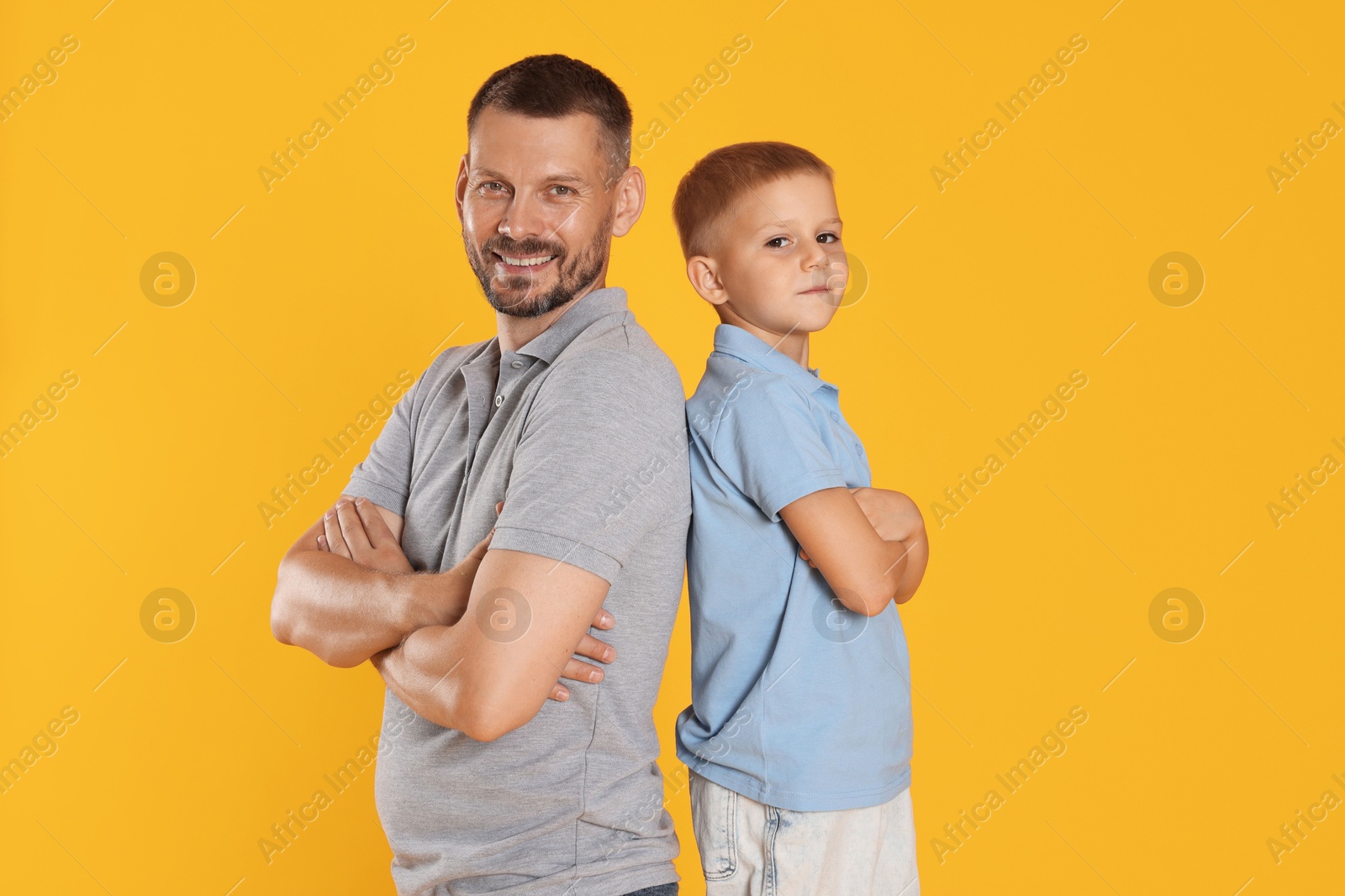 Father and son posing together on yellow background Photo of Father and son posing together on yellow background