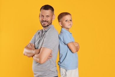 Photo of Father and son posing together on yellow background