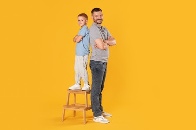 Photo of Father and son posing together on yellow background
