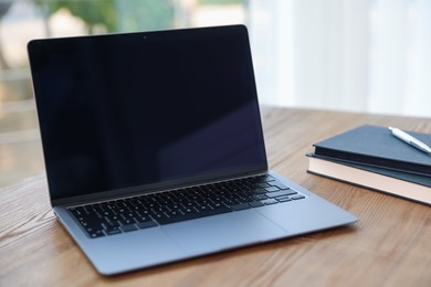 Photo of Home workspace. Laptop and stationery on wooden desk indoors, closeup