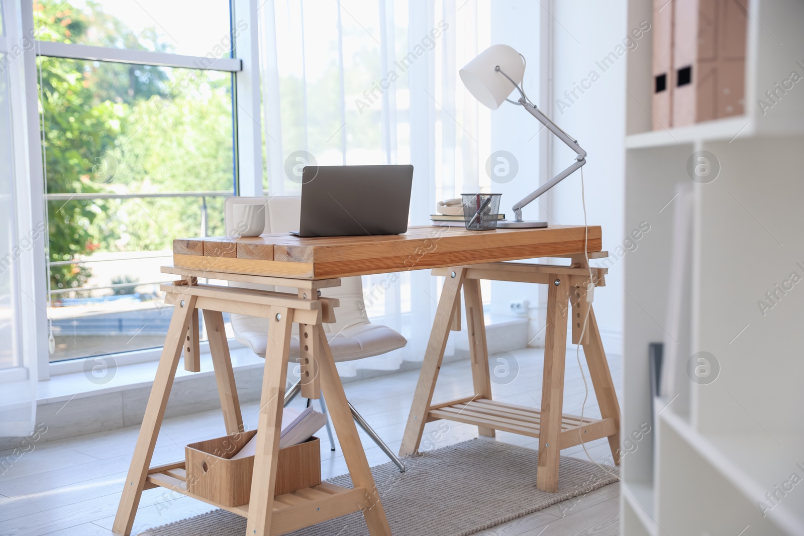 Photo of Home workspace. Laptop and stationery on wooden desk near window indoors