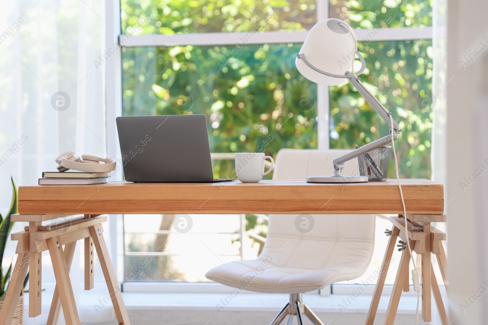 Photo of Home workspace. Laptop and stationery on wooden desk near window indoors
