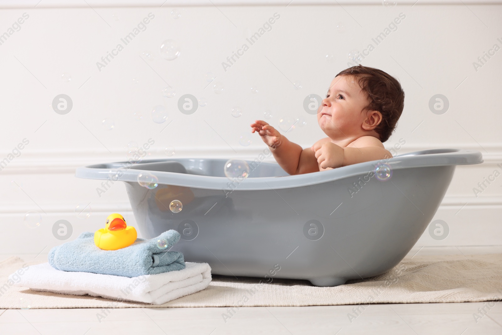 Photo of Cute little baby bathing in tub at home