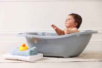 Photo of Cute little baby bathing in tub at home