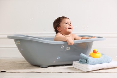 Photo of Cute little baby bathing in tub at home