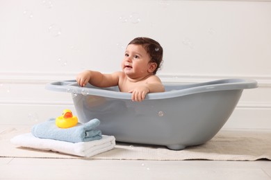 Photo of Cute little baby bathing in tub at home
