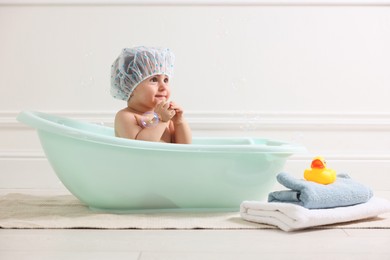 Photo of Cute little baby in cap bathing at home
