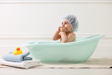 Photo of Cute little baby in cap bathing at home