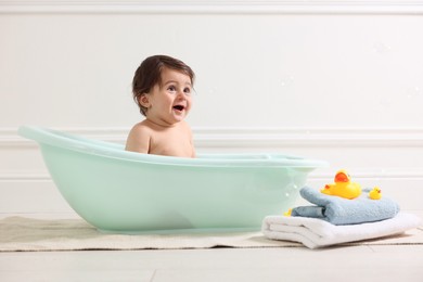 Photo of Cute little baby bathing in tub at home