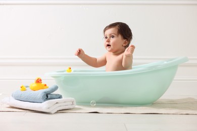 Photo of Cute little baby bathing in tub at home