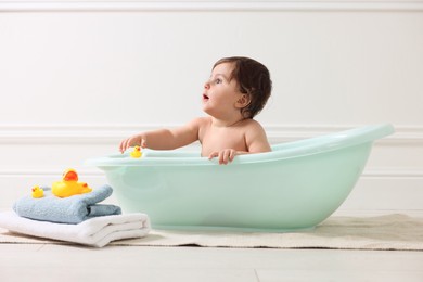 Photo of Cute little baby bathing in tub at home