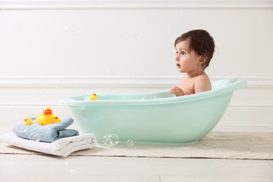 Photo of Cute little baby bathing in tub at home