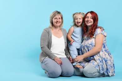 Photo of Pregnant woman, her mother and daughter on light blue background, space for text