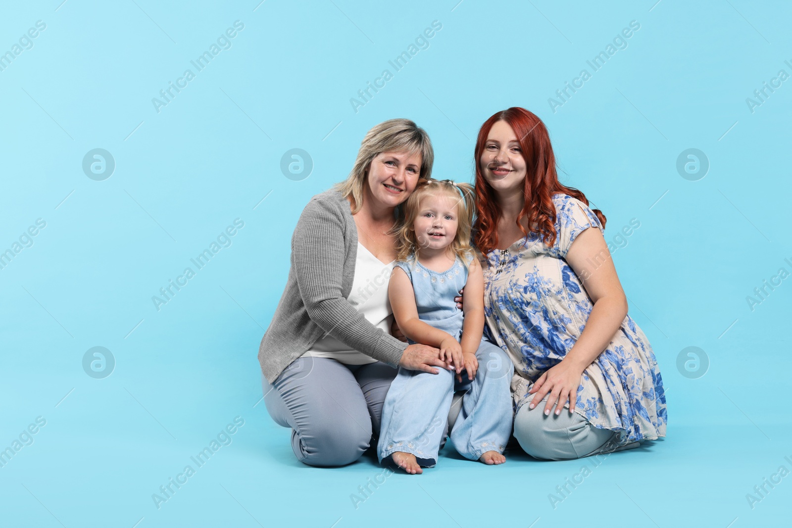 Pregnant woman, her mother and daughter on light blue background, space for text Photo of Pregnant woman, her mother and daughter on light blue background, space for text