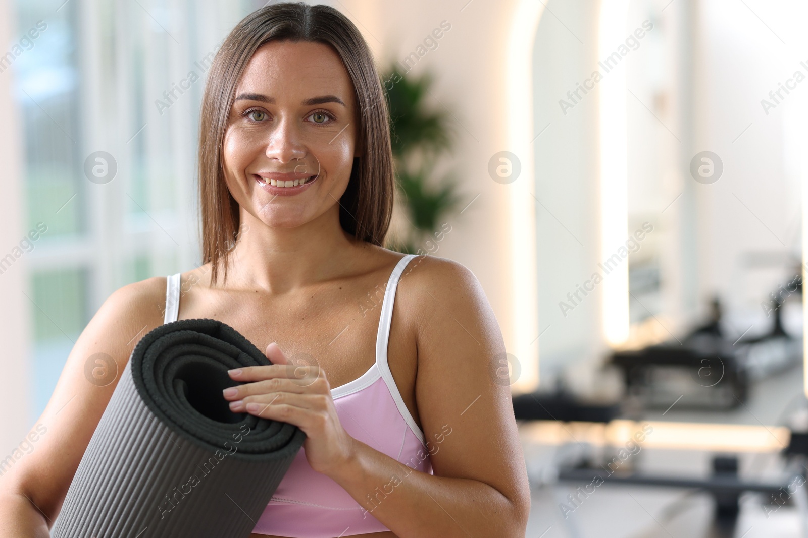 Photo of Woman with fitness mat in pilates studio, space for text