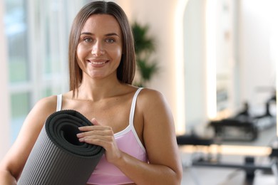 Photo of Woman with fitness mat in pilates studio, space for text