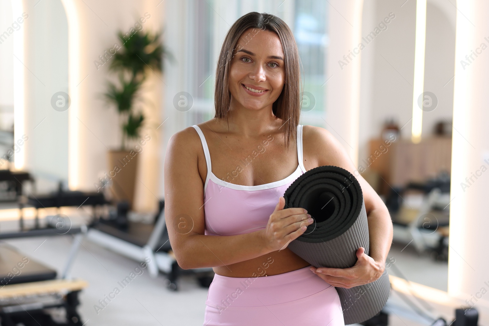 Woman with fitness mat in pilates studio Photo of Woman with fitness mat in pilates studio