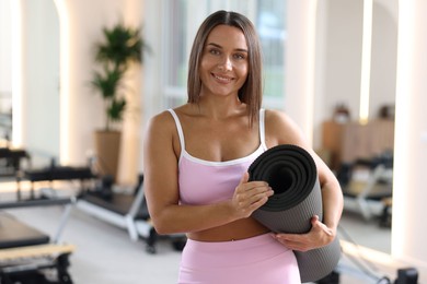 Photo of Woman with fitness mat in pilates studio