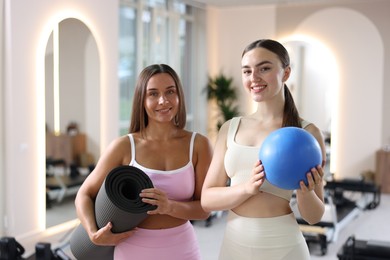 Photo of Women with fitness mat and ball in pilates studio
