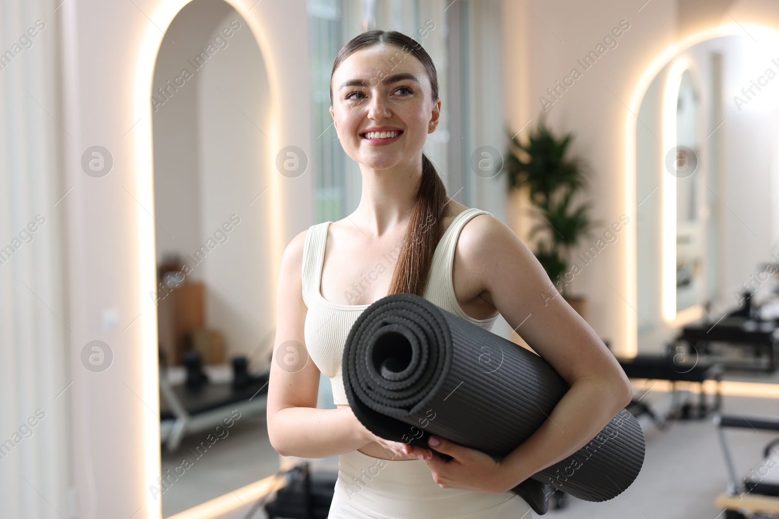 Photo of Woman with fitness mat in pilates studio
