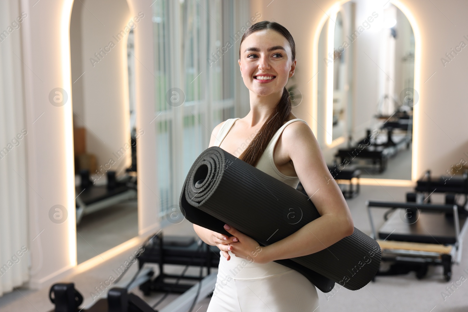 Photo of Woman with fitness mat in pilates studio, space for text