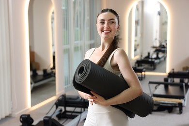 Photo of Woman with fitness mat in pilates studio, space for text