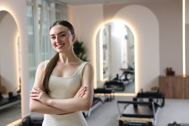 Photo of Happy woman wearing sportswear in pilates studio, space for text