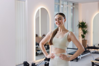 Photo of Happy woman wearing sportswear in pilates studio, space for text
