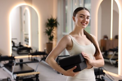 Photo of Woman with foam blocks in pilates studio, space for text