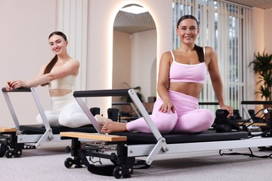 Photo of Woman and pilates instructor on reformers in studio