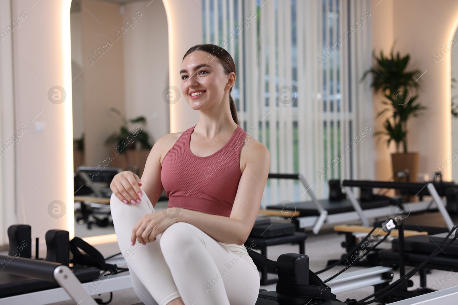 Photo of Woman sitting on reformer in pilates studio