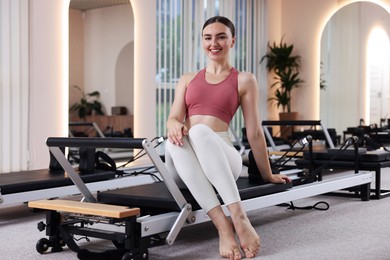 Photo of Woman sitting on reformer in pilates studio