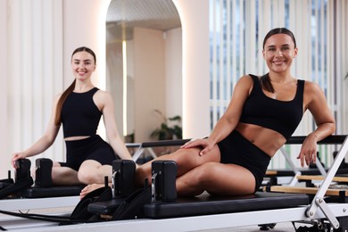 Photo of Woman and pilates instructor on reformers in studio