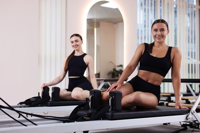 Photo of Woman and pilates instructor on reformers in studio