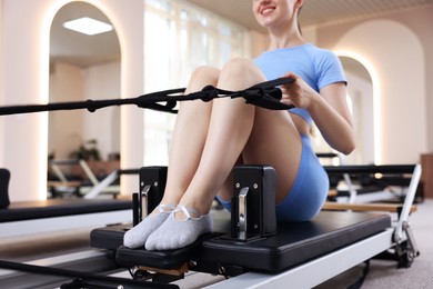 Photo of Woman exercising on reformer in pilates studio, closeup