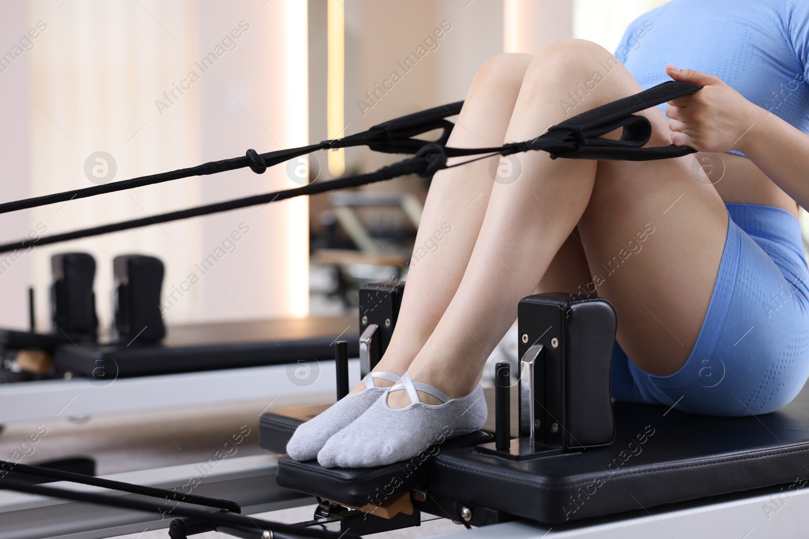 Photo of Woman exercising on reformer in pilates studio, closeup