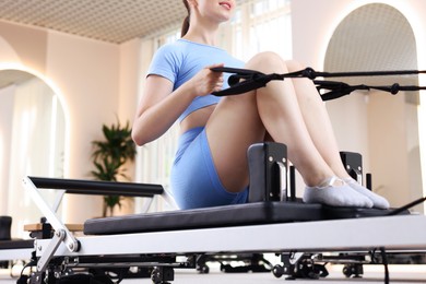 Photo of Woman exercising on reformer in pilates studio, closeup