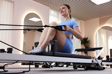 Photo of Woman exercising on reformer in pilates studio, low angle view
