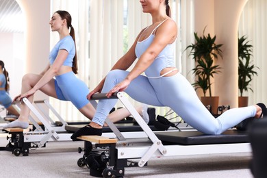 Photo of Woman and pilates instructor exercising on reformers in studio