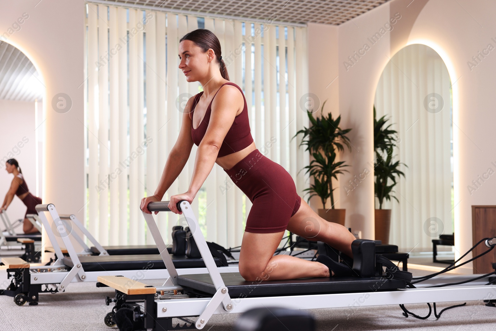 Woman exercising on reformer in pilates studio Photo of Woman exercising on reformer in pilates studio