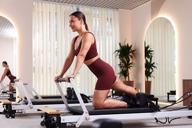 Photo of Woman exercising on reformer in pilates studio