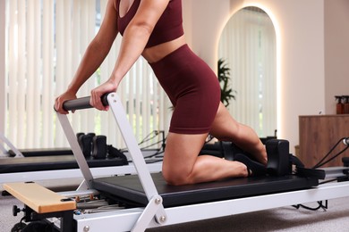 Photo of Woman exercising on reformer in pilates studio, closeup