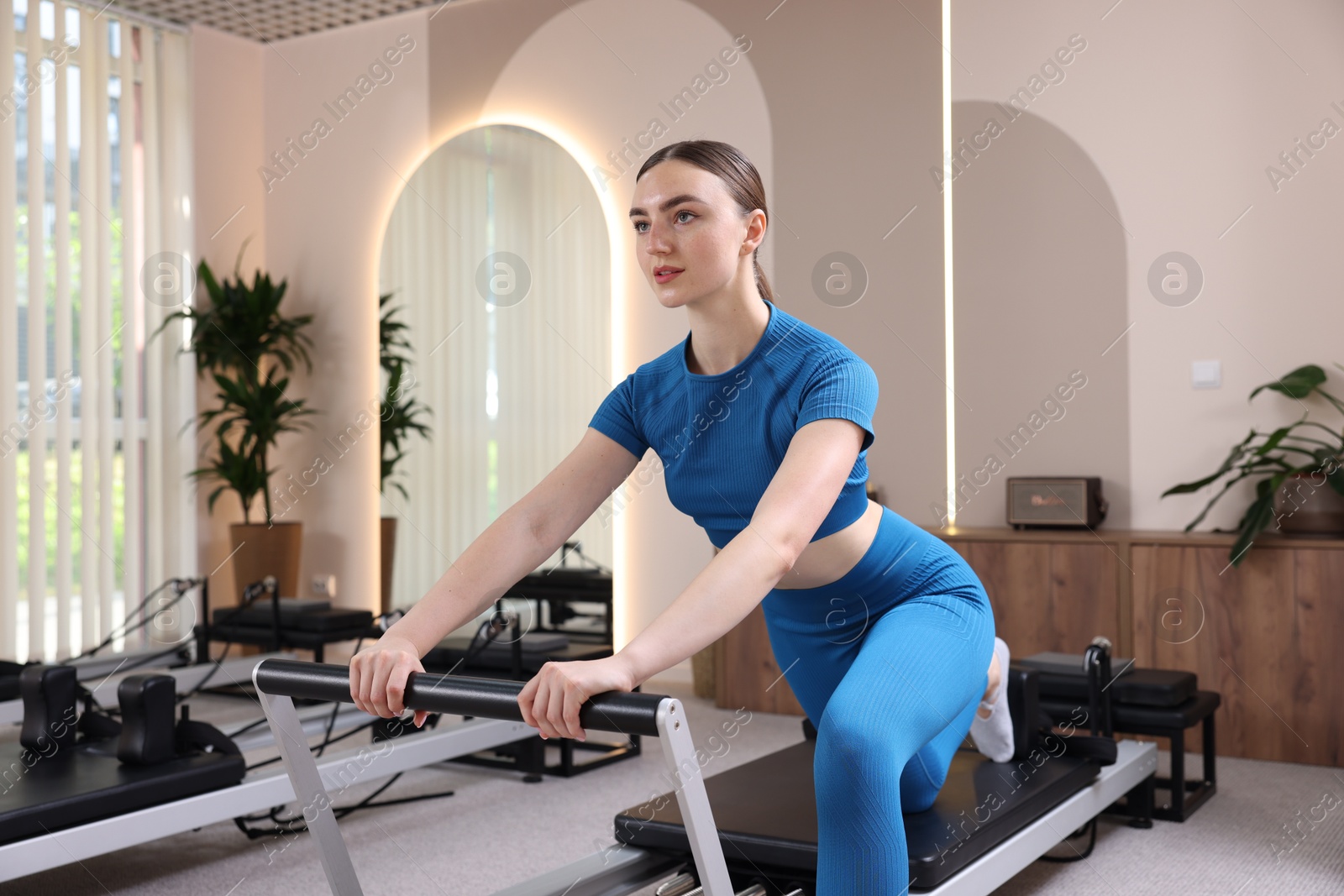 Photo of Woman exercising on reformer in pilates studio