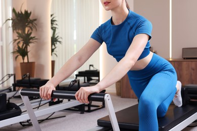 Photo of Woman exercising on reformer in pilates studio, closeup