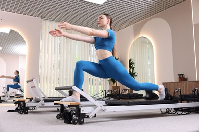 Photo of Woman exercising on reformer in pilates studio, low angle view