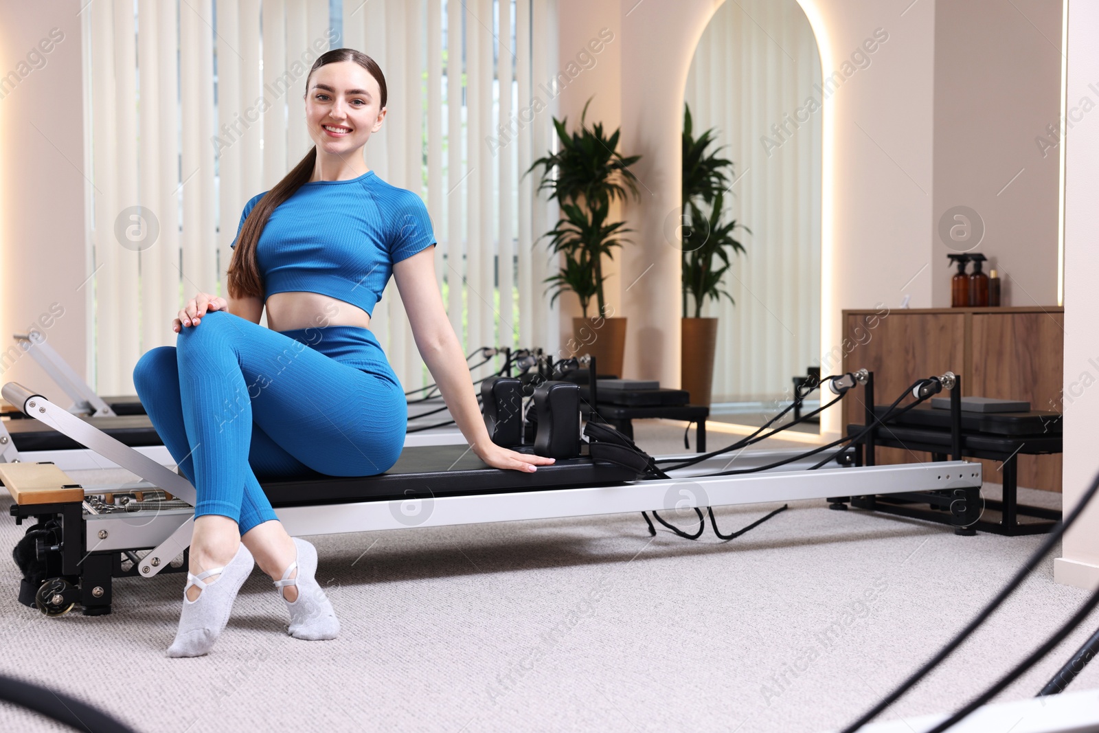 Photo of Woman sitting on reformer in pilates studio
