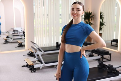Photo of Happy woman wearing sportswear in pilates studio, space for text
